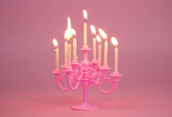 Pink candelabra with candles on pink background.	