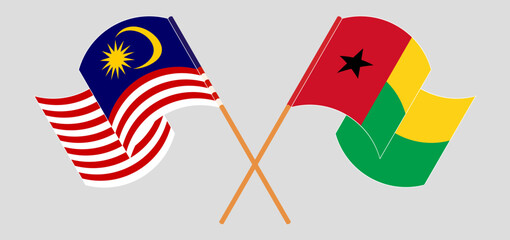 Crossed and waving flags of Malaysia and Guinea-Bissau