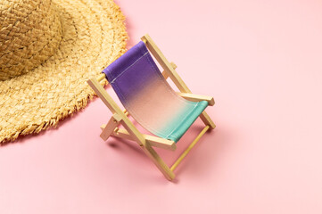 Colorful beach chair, straw hat on pink background. Summer, holidays and beach concept. Creative...