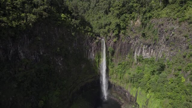 Aerial view of Cannabullen Falls surrounded by lush forest and vertical cliffs, Koombooloomba, Queensland, Australia.