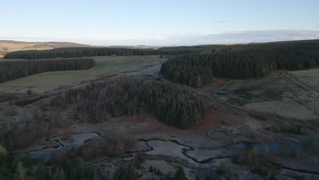 Aerial view of serene forest and meadow by Carter Burn, Jedburgh, Scotland.