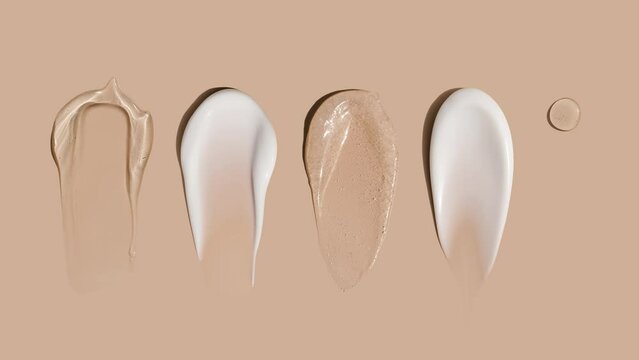 brush strokes of creamy texture of cosmetic samples on a pastel beige background