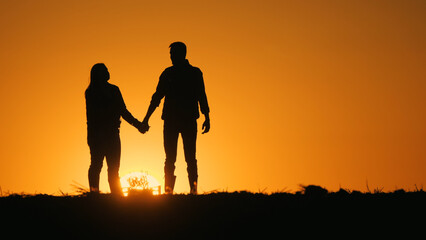 Silhouettes of a romantic couple. Holding hands and standing against the backdrop of a beautiful...