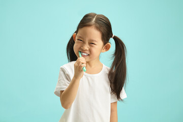 Face of Japanese child girl cleaning mouth with a brush for morning routine and oral self care....
