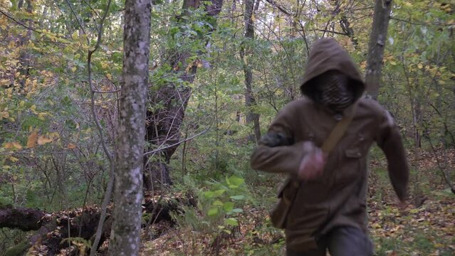 A maniac or criminal in a mask runs through the forest