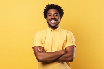 Obraz premium Portrait of a joyful afro-american man in his 20s with arms crossed isolated in pastel yellow background