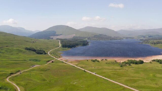 Aerial view of Loch Tulla surrounded by majestic mountains and lush greenery, Highlands, United Kingdom.