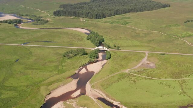 Aerial view of Loch Tulla with winding river and lush forest, Highlands, United Kingdom.