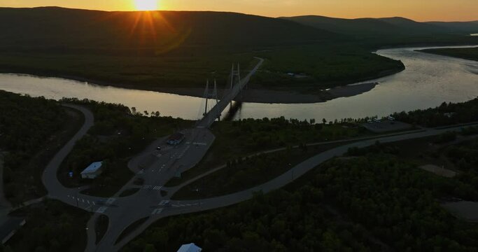 Drone rising toward the Sami Bridge and the Tenojoki river, midnight sun in Utsjoki, Finland