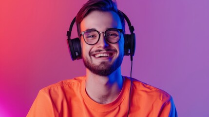 Stylish young man in an orange shirt with headphones enjoying music in a colorful purple background