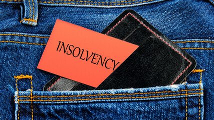 Debt relief concept. A word INSOLVENCY on business cards from a purse from a jeans pocket