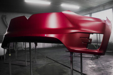 Painted parts of car body using spray gun, drying body in the paint chamber after applying the...