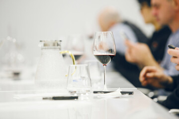 Filled Glass with Red Wine on Table During Degustation. Focused Wine Tasting in Progress, Close up...