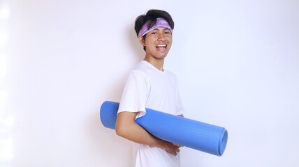 Excited young man holding a yoga exercise mat