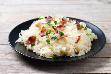 Slovak potato dumplings halusky with steamed sauerkraut and bacon on wooden table