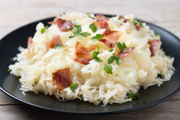 Slovak potato dumplings halusky with steamed sauerkraut and bacon on wooden table. Close up