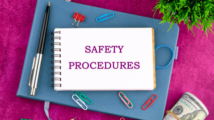 Safety Procedures concept. SAFETY PROCEDURES written on a blank sheet of notepad in a composition with pens, paper clips, dollars and a green plant