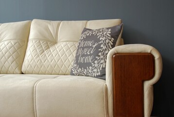 a cream couch with blue pillows against a blue wall with a wooden base