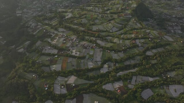 Aerial view of Batur Volcano, farmland, and lake at sunrise with clouds over Pinggan, Kintamani, Bali, Indonesia.