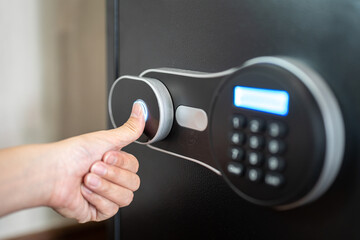 Action of people hand is unlocking to open the safe box door by scanning fingerprint on the on the sensor. Close-up and selective focus.