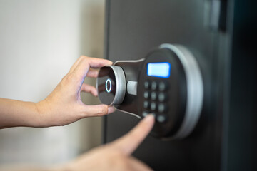 Action of people hand is unlocking to open the safe box door by pressing password on the number...