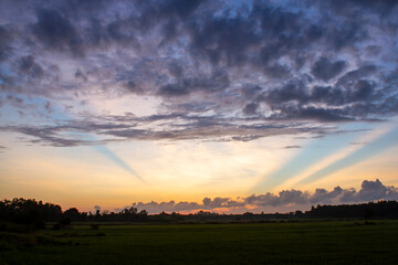 Sunrise with clouds and light rays at a field in Vietnam countryside.