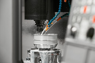 CNC milling machine cutting aluminium automotive part with a coolant liquid. Hi-Technology...