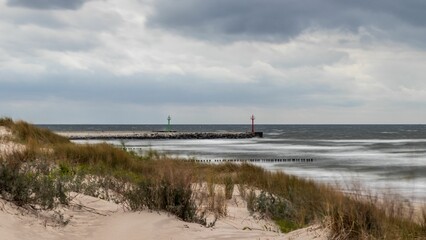 Scenic landscape with a pier surrounded by green bushes against a cloudy sky