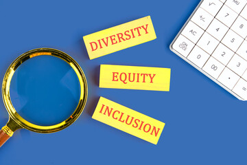 Diversity, equity, inclusion DEI symbol. Business, diversity, equity, inclusion concept. DIVERSITY EQUITY INCLUSION on wooden blocks in a composition with a magnifying glass and a calculator, top view