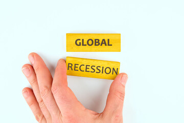 Business and global recession concept. Copy space. Global recession symbol on wooden blocks on a light background laid out with the help of a hand