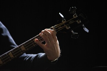 Closeup of a bass player at concert at dim lighting