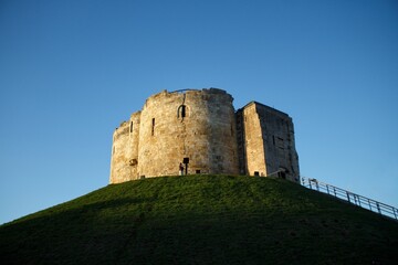Closeup of a  majestic castle atop a lush hill under the blue sky in the UK