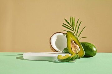 A half of coconut and a petri dish containing avocado slices displayed next to a round shaped podium. Front view. Abstract composition in minimal design