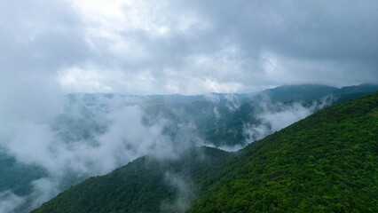 Idyllic landscape of a lush green valley surrounded by towering mountains, shrouded in a fog