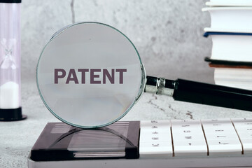 Business Team Concept. Word PATENT written through a magnifying glass on a gray background. Black and white image