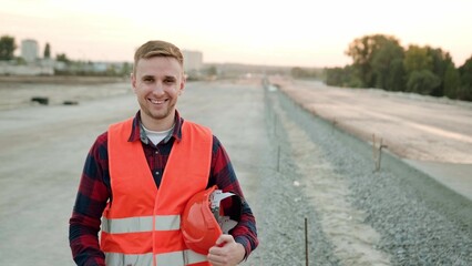 Smiling professional builder in protective clothes working on site