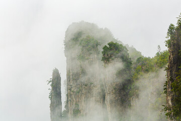 Limestone karst mountains in Enshi Grand Canyon National Park partly shrouded in fog, Hubei...