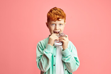 Happy Red Boy Eats Chocolate Bar, Headshot Isolated Portrait On Pink Isolated