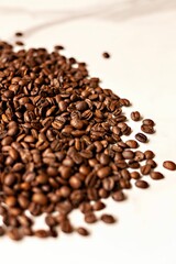 Heap of freshly roasted coffee beans on a bright white background.