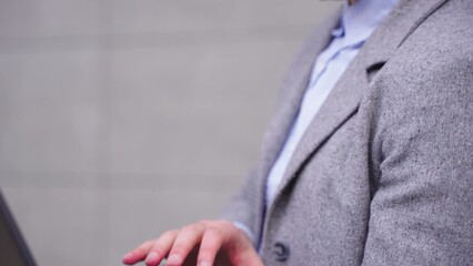 Calm young businessman typing on the laptop outdoors. Slow motion