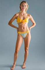 Fototapeta premium Full-length photograph of a young woman in a swimsuit, isolated on gray background