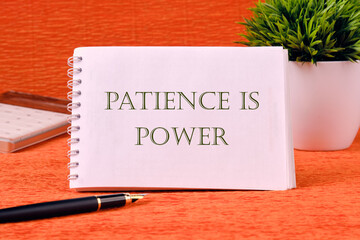 Personal development concept. Words PATIENCE IS POWER on a white notebook on an orange background