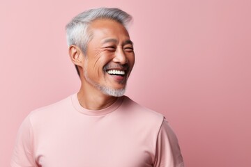 Obraz premium Portrait of a glad asian man in his 70s laughing isolated in solid pastel color wall