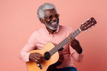 Portrait of a satisfied afro-american man in his 60s playing the guitar on solid pastel color wall