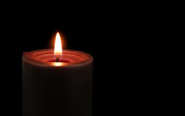 Close-up of black candle burning and melting on black background close-up.