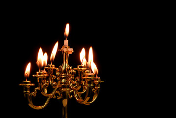 Candelabra with white burning candles isolated on black background. Copy space for text.