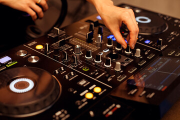 Close up portrait of female disc jockey hands mixing tracks on professional sound mixer, playing music at nightclub. Dj, disco, discotheque concept.