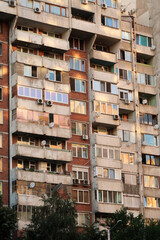 Obraz premium Orange, yellow, pink reflection of the sunset in the many windows of a concrete, socialist, brutalist panel, multi-story, high-rise, apartment block, building, Sofia, Bulgaria