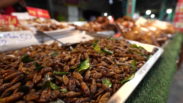 Shallow focus of heap of fried silk worms pupae for sale in Thailand