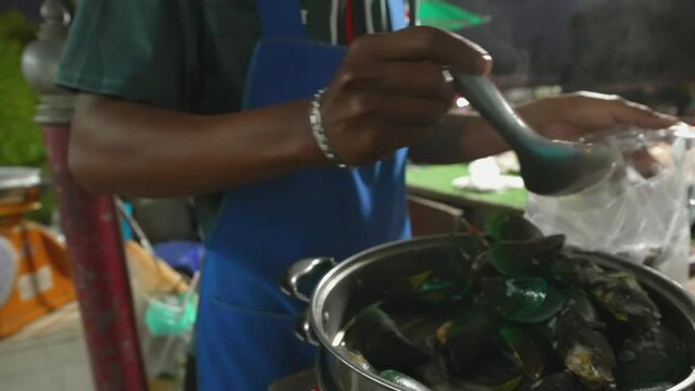 Street vendor filling Mussels seafood in a bazaar street market in Thailand